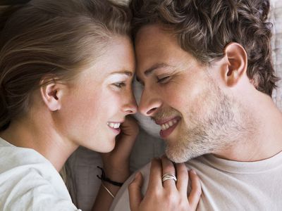 Couple in bed close up, smiling at each other