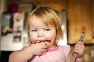 Young Girl Eating Brownie Mix In Kitchen