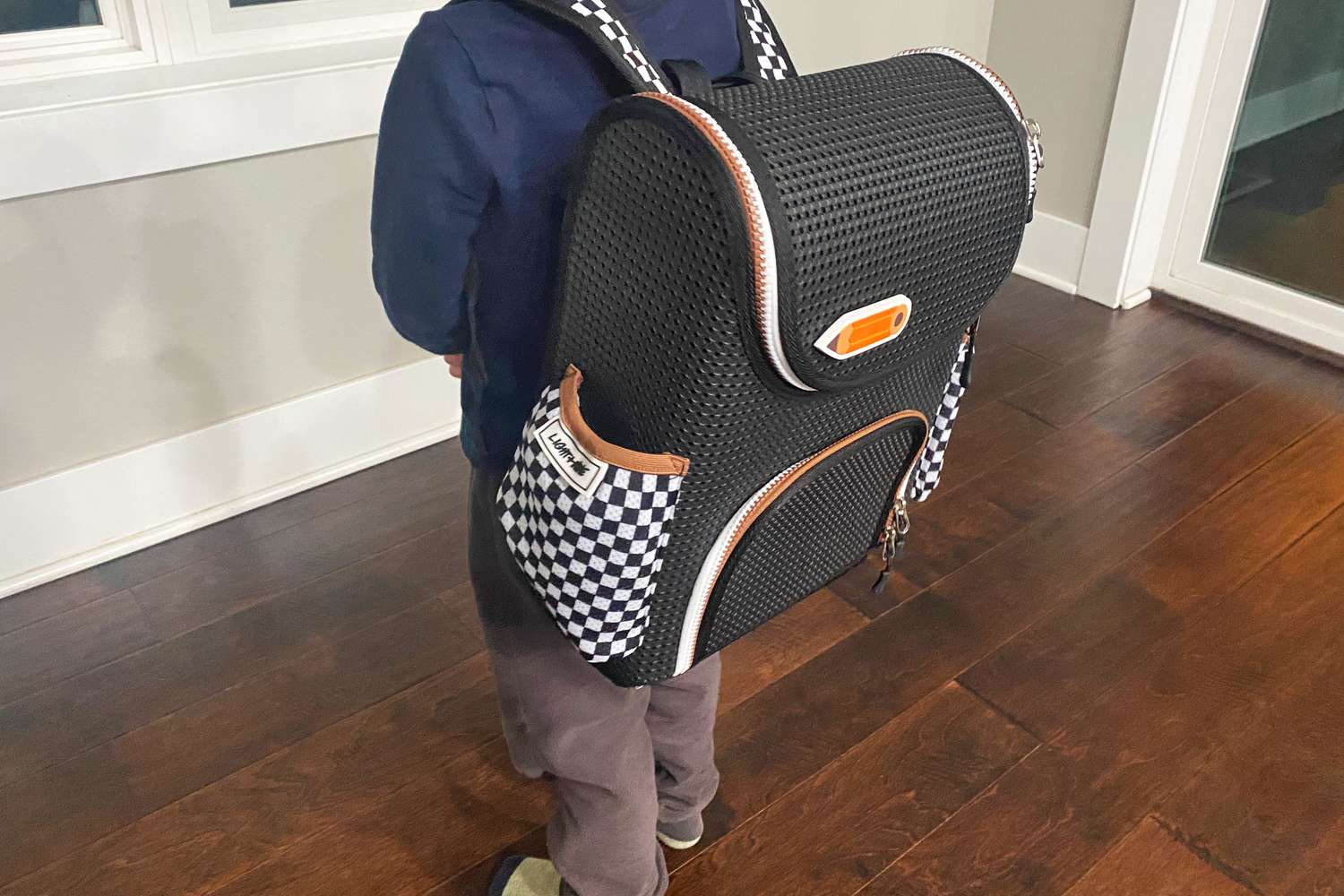 Person wearing Light + Nine Checkered Starter Backpack and standing on wooden floor