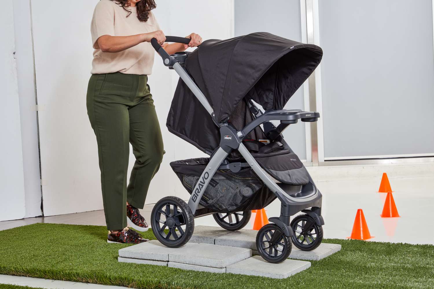 Person walking Chicco Bravo Trio Travel System on stone surface