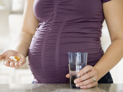 Pregnant woman in a purple shirt taking medicine.