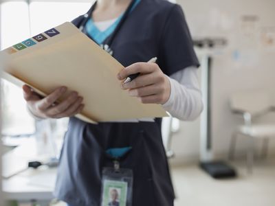 Nurse in scrubs holding medical chart in clinic