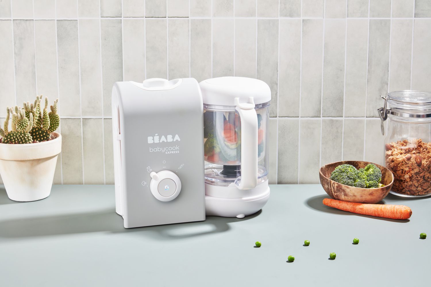 The BÃ©aba Babycook Express Baby Food Maker on a kitchen counter surrounded by food.