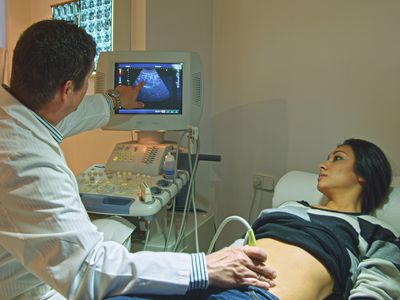 Doctor using ultrasound on pregnant woman