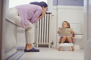 child and parent working on potty training in a bathroom