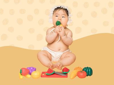 6-Month Old baby playing with a cutting fruit set on an orange background