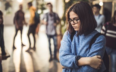 一个十几岁的女孩在学校走廊里看起来很伤心