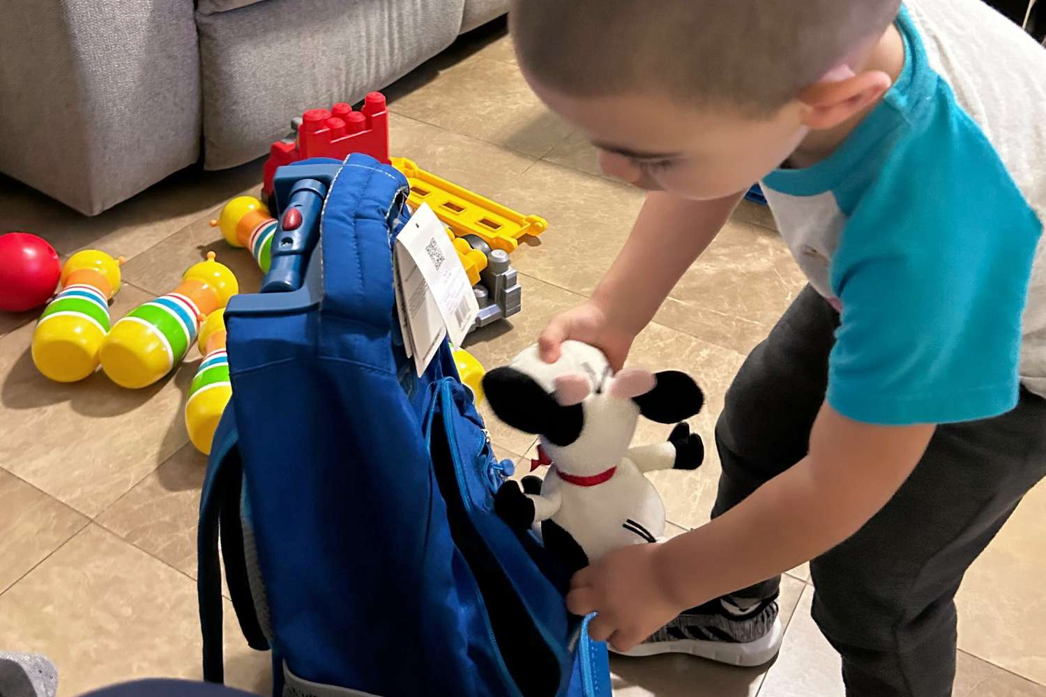 Kid placing soft toy inside JWorld Sunrise Rolling Backpack