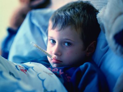 Young boy (3-5) in bed, thermometer in mouth, portrait