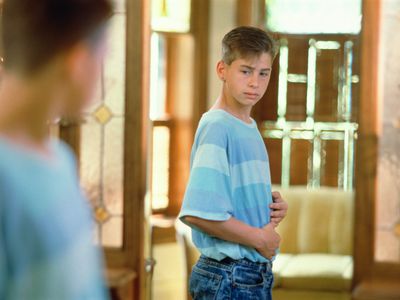 fitness and puberty - teen boy looking in mirror