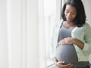 黑人孕妇抱着肚子站在窗边