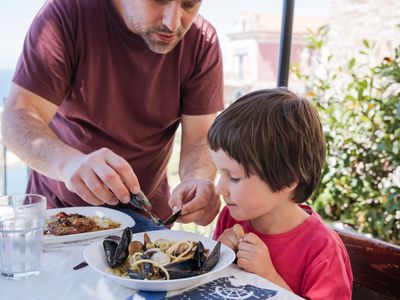 Dad serving pasta with mussels to child
