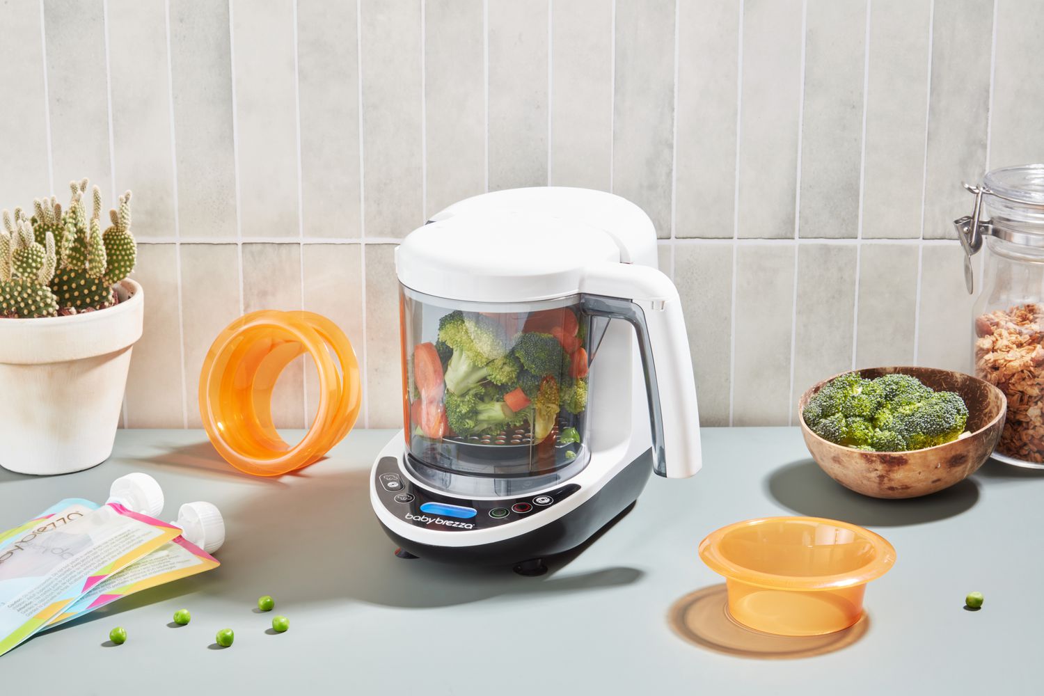 A loaded Baby Brezza One Step Glass Baby Food Maker sits on a kitchen counter.
