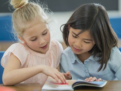 Two elementary school friends looking at a book