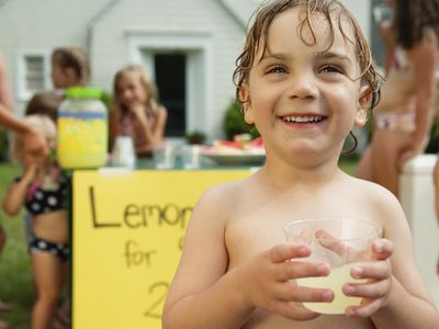 Little boy holding glass in front of lemonade