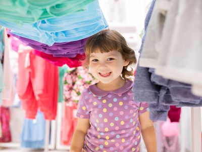 Toddler playing in clothing racks