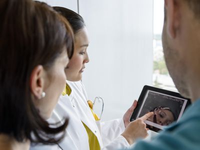 Female doctor using digital tablet with couple to explain blocked fallopian tubes