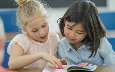 两个小学生朋友在看一本书
