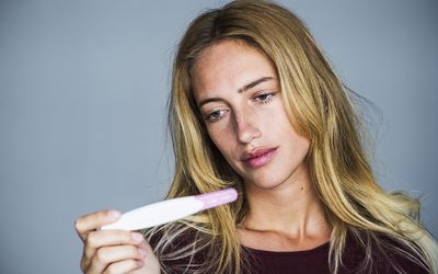 年轻女子失望地看着验孕棒华体会体育官方人口