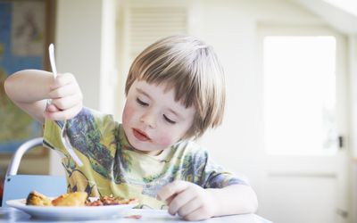 Young boy eating dinner in kitchen