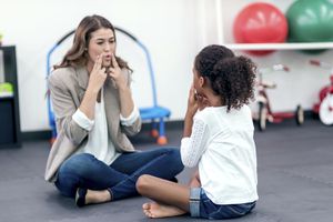 成年女性治疗师指导年轻女孩进行语言治疗