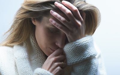 穿着毛衣的女人抱着头，因为不孕而感到沮丧和焦虑