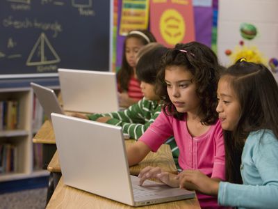 Students typing on laptop in classroom