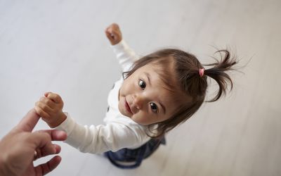 小孩抓着父母的手指，抬头看着镜头