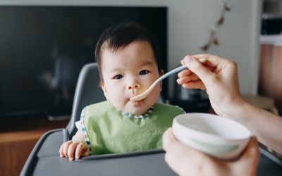 婴儿坐在高脚椅上被喂食