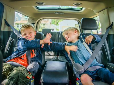 Twin brothers sitting in back of vehicle, fighting