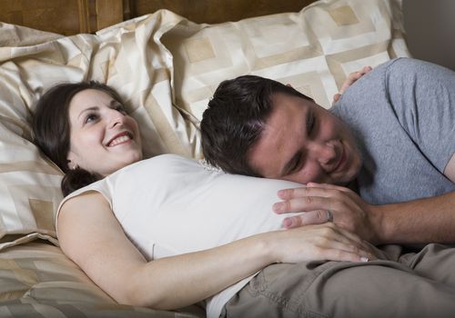 伴侣抱着妈妈怀孕的腹部