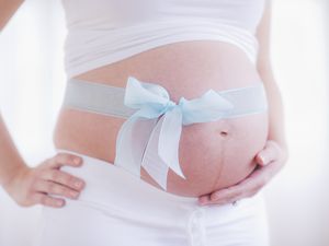 孕妇的肚子上缠着蓝丝带