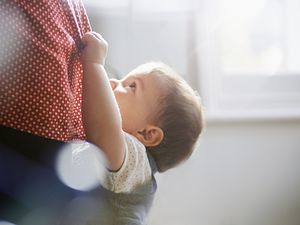 蹒跚学步的孩子紧紧抓住妈妈的裙子