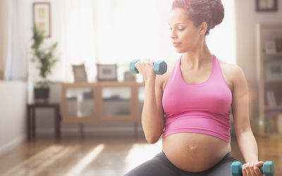 Pregnant mixed race woman exercising with dumbbells