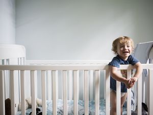 幼儿站在婴儿床上微笑