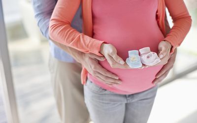 一对穿着粉色和蓝色婴儿靴的孕妇