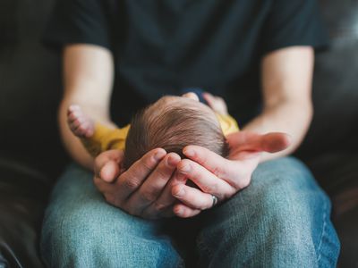 Man cradles baby in hands.