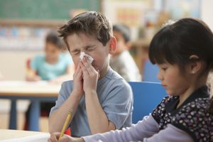 Caucasian boy blowing nose in classroom