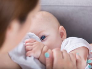 可爱的蓝眼睛婴儿在哺乳时看着妈妈