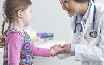 Doctor examining little girl's hand