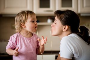 Mother and child eating spaghetti together