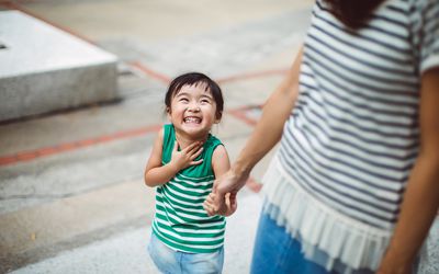 在公园里和妈妈手牵着手微笑的孩子