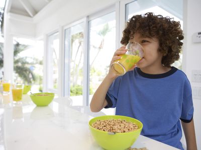 男孩at table, drinking orange juice