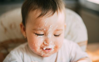 脸上有乳清干酪的婴儿