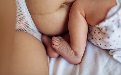 新生儿腿的特写，旁边是他们妈妈的肚子和腿
