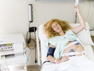 Pregnant woman in hospital bed making pained face