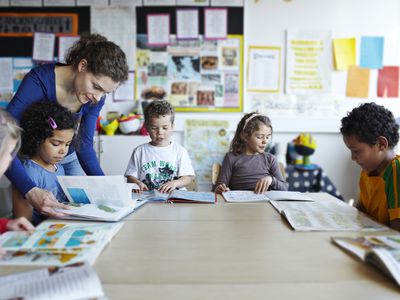 Teacher looking at books with young children
