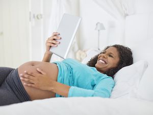 孕妇在床上使用平板电脑