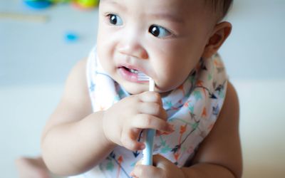 亚洲婴儿用两只手拿着牙刷