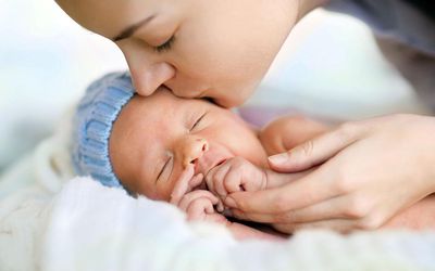 Close up of sleeping newborn and kissing mother